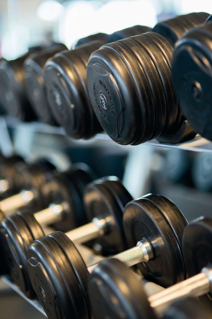 Strona główna Close-up view of black dumbbells neatly arranged on a rack in a gym.